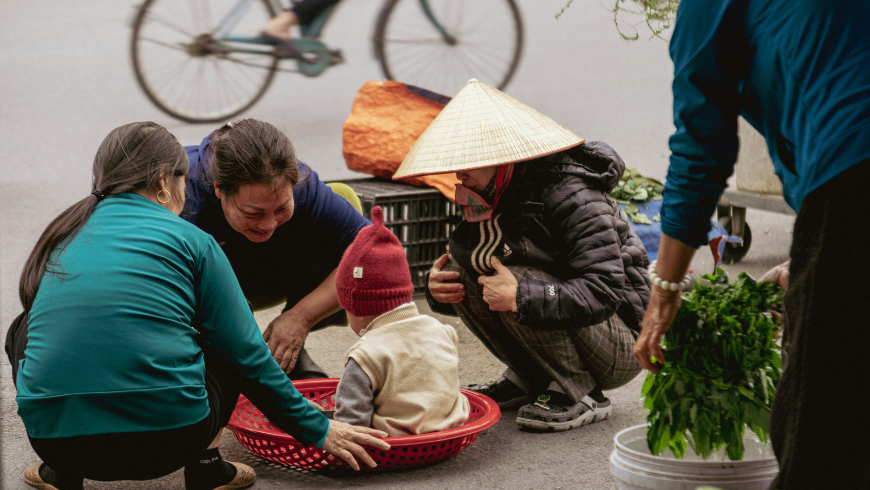 People gathered around a child in a basket at market