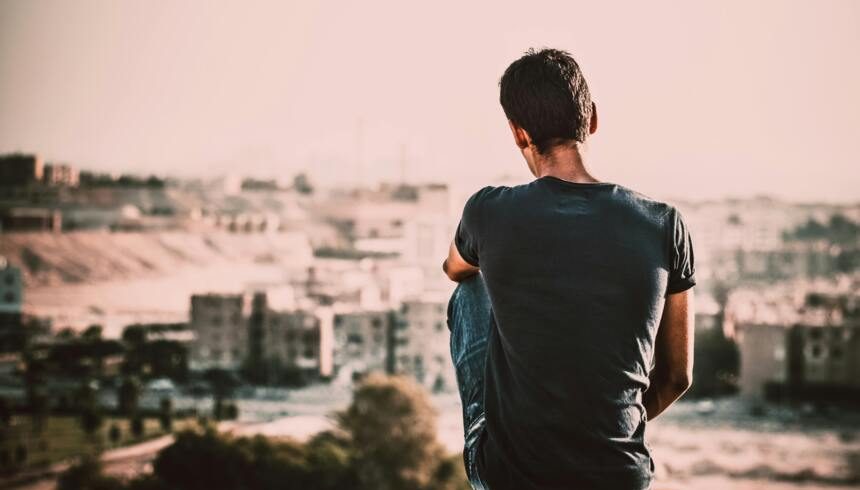 Person sitting and looking over a city skyline at sunset.