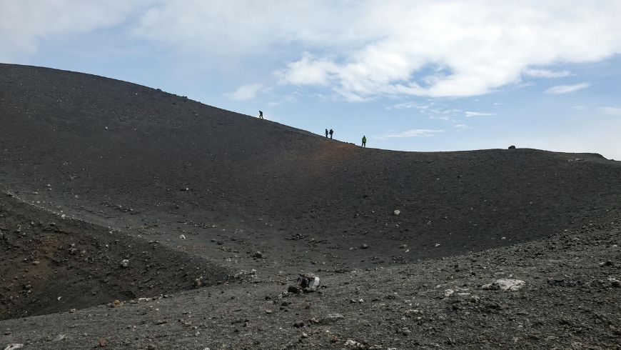 Hikers Trekking Across Volcanic Landscape