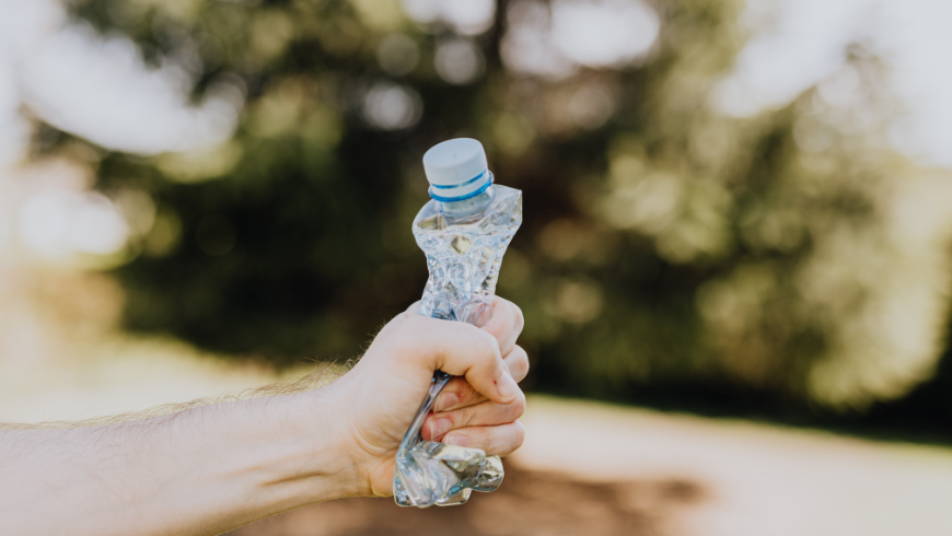 A hand tightly squeezing a plastic bottle, symbolizing the fight against plastic pollution.