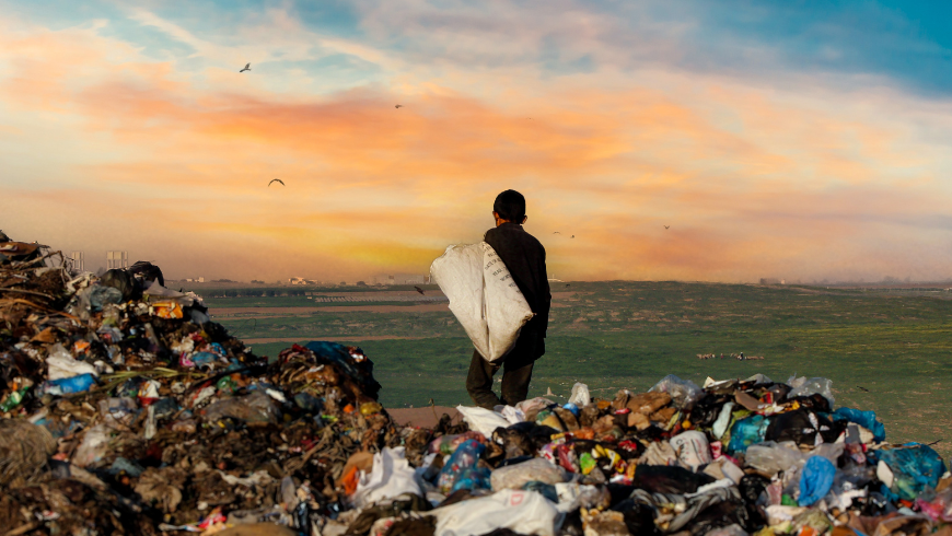 Man standing by the sea at sunset with trash on the beach, highlighting plastic pollution.