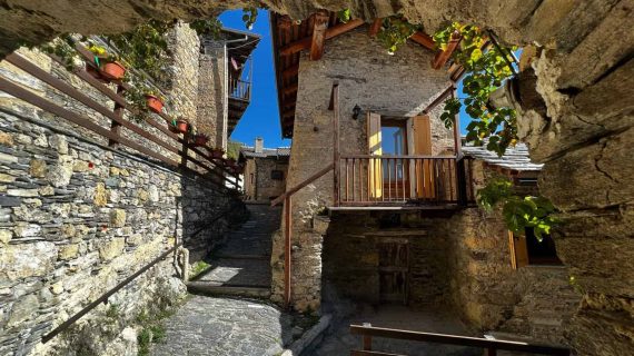A traditional house in Serremorello stands bathed in natural light, framed by the soft tones of the alpine landscape.