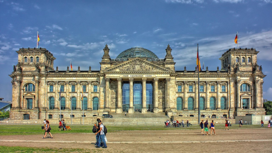 Sustainable Berlin travel: Reichstag building with glass dome and people walking in front
