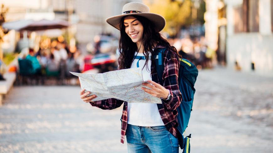Solo trip in a city: girl consulting a paper map instead of her cell phone