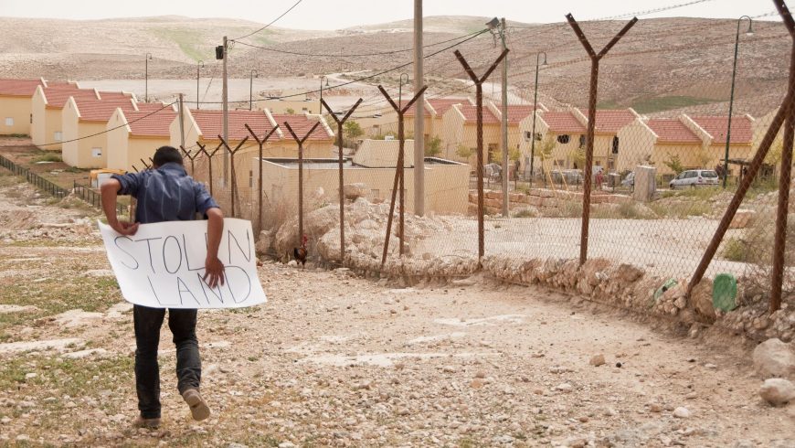 Man near a border with a sign that says "stolen land"
