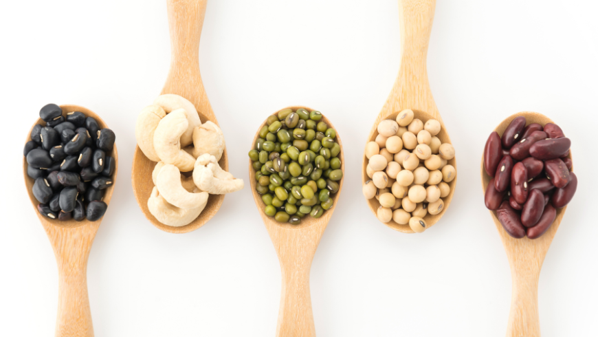 Wooden spoons filled with different types of dried legumes, rich in fiber and plant proteins for a healthy and sustainable diet.