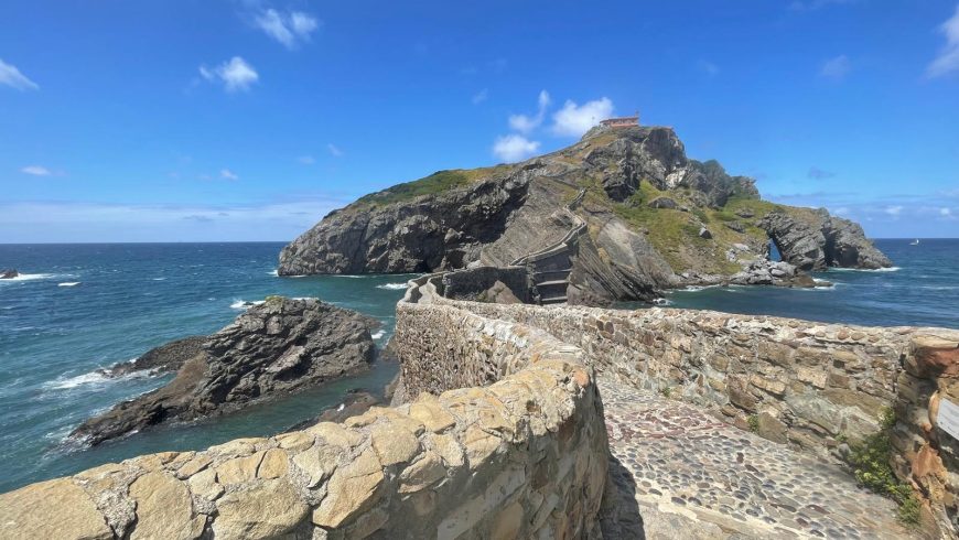 San Juan de Gaztelugatxe on the Basque coast, Spain, showing the stone bridge and staircase leading to the historic hermitage, a protected site with advance visitor reservations.