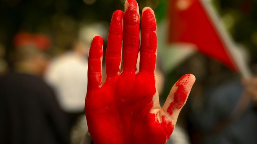 Red-painted hand of an activist protesting to stop the genocide in Palestine
