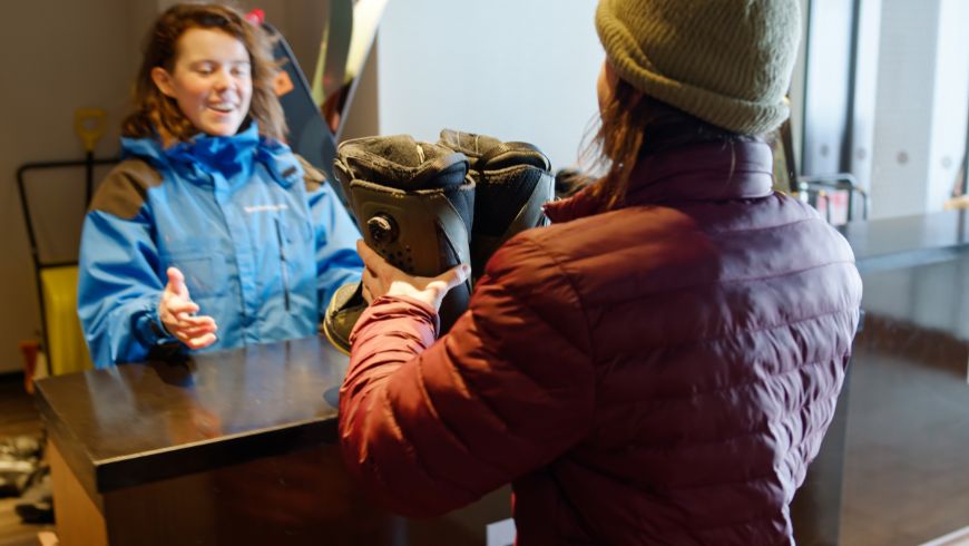 Young woman renting mountain boots for an outdoor adventure.