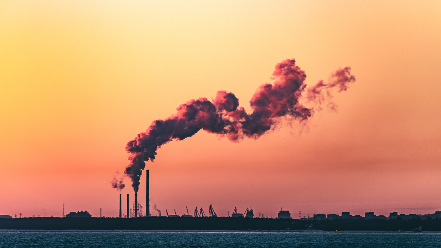 Industrial landscape at sunset with chimneys releasing dark smoke