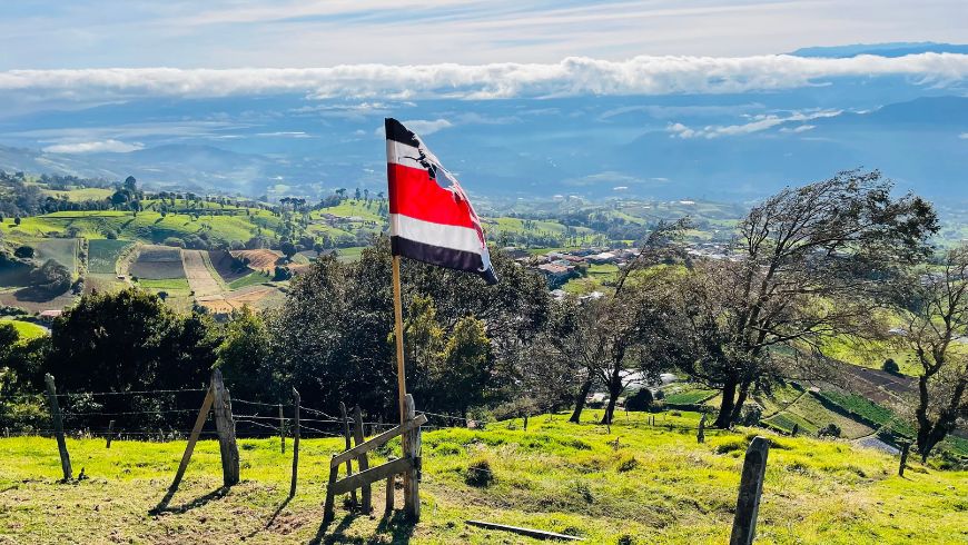 Rican flag in the foreground, overlooking the green hills of Cartago from the mountains, Costa Rica.