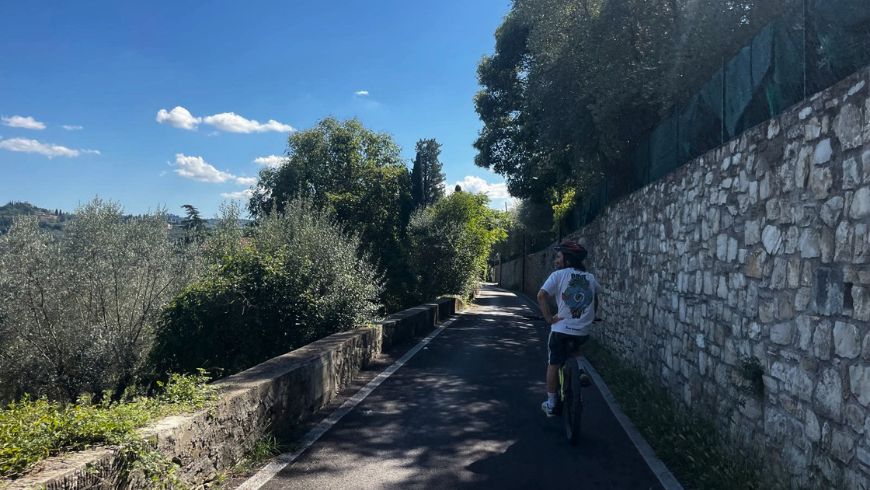Cycling along a secondary road near Florence, between dry-stone walls and the Tuscan hills.