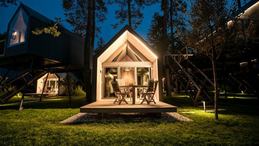 Drei leuchtende Bell-Zelte auf einem Glamping-Platz bei Nacht unter einem Vollmond, umgeben von Bäumen.