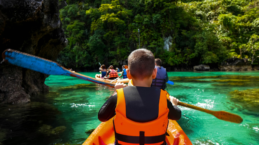 Kinder, die in einem Fluss Kayaks fahren