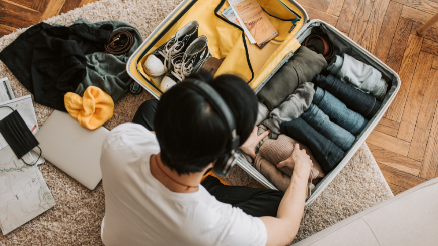 Junger Mann bereitet seine Reise vor und packt seinen Koffer mithilfe einer digitalen Packliste.