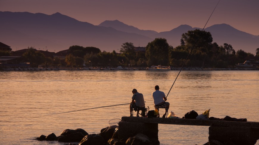 Atardecer en el río Mara, dos pescadores sentados en las rocas de la orilla, Liguria