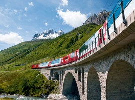 Recorrido del tren Glacier Express sobre un puente y al fondo la vegetación y las montañas
