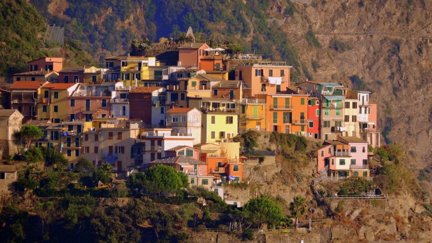 Paisaje de varias casas de colores puestas juntas una sobre la otra sobre la montaña, Liguria