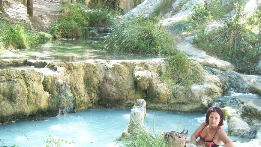 Cascade naturelle des thermes de San Filippo avec bassin d’eau et personne se baignant.