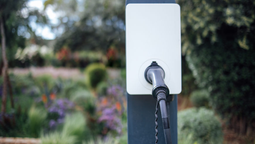 Prise de recharge pour voiture électrique installée à l’extérieur dans un environnement naturel et verdoyant.