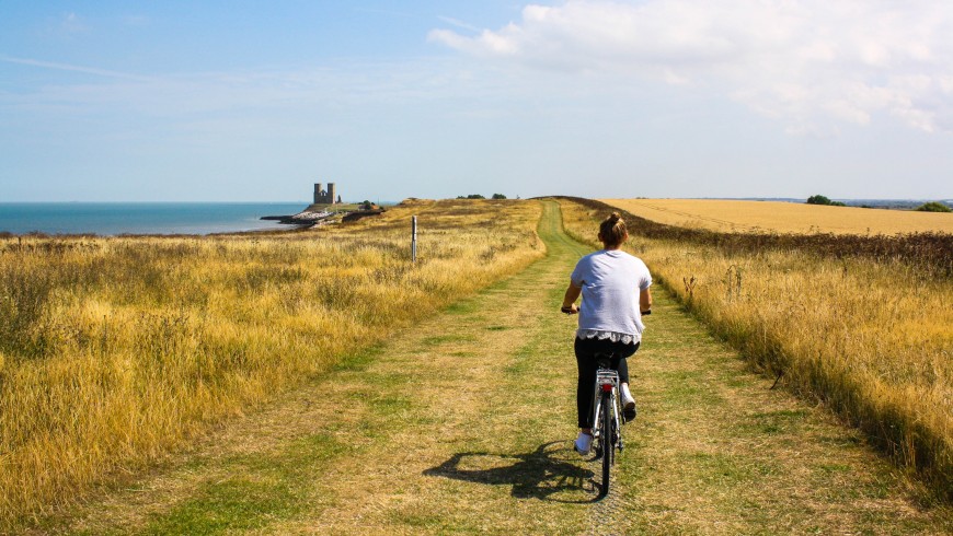 fille à vélo dans la nature avec vue sur la mer, exemple de tourisme durable