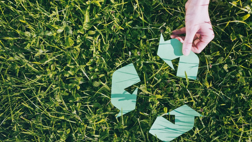 avantages hébergement écoresponsable : main ramassant des déchets en papier dans l’herbe, symbole d’un engagement pour la protection de l’environnement. Elle illustre l’importance d’un comportement responsable et durable, notamment lors des voyages.